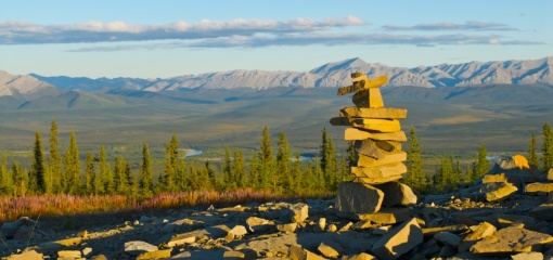Photograph of a stone inukshuk in front of mountains