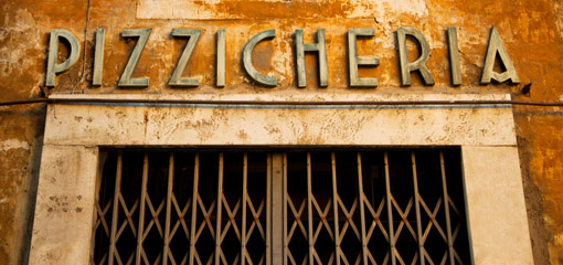 Photograph of the sign 'Pizzicheria' above a closed gated entrance
