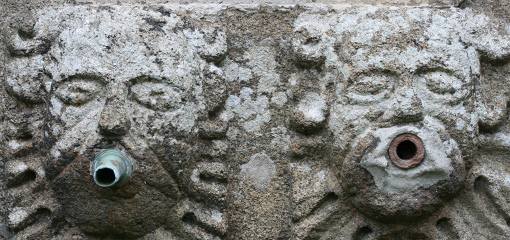 Photograph of two faces in a stone fountain