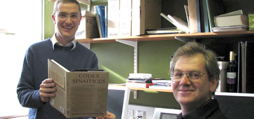 Photograph of two lecturers, one seated and one holding a publication on Codex Sinaiticus