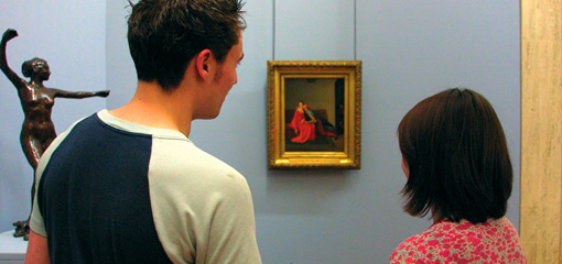 Photograph of two students studying a painting