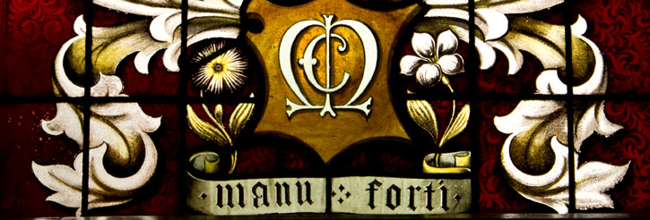 Photograph of stained glass window with 'manu forti'