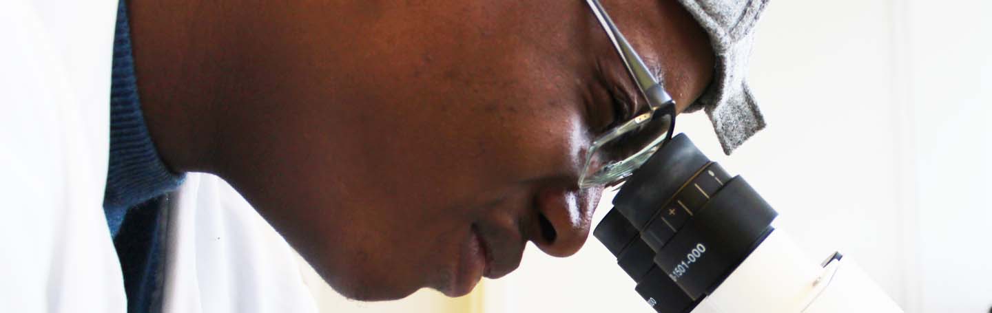 male looking through a microscope