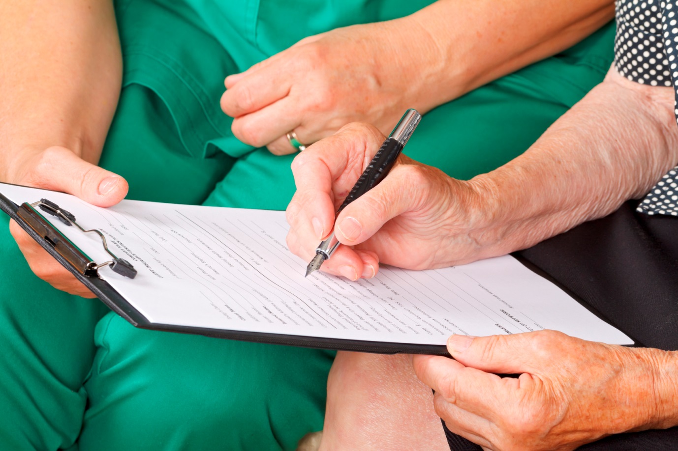 elderly patient completing a form with healthcare worker
