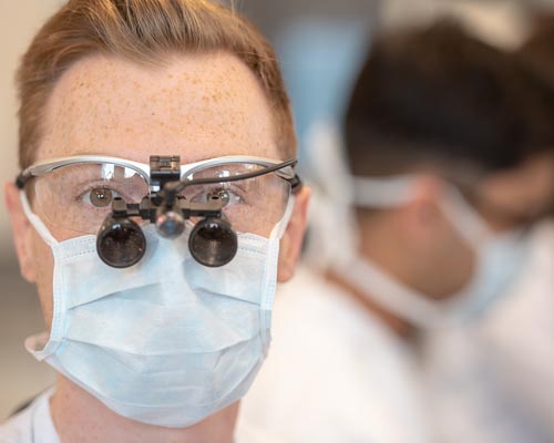 Male dental student wearing facemask and magnifying glasses