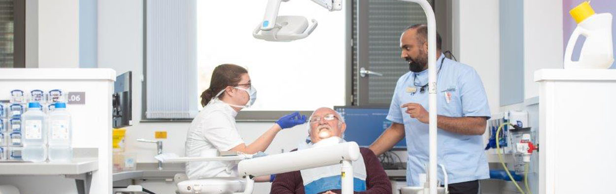 Two dentists looking over a male in a dentists chair