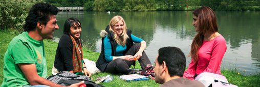 students sitting by lake