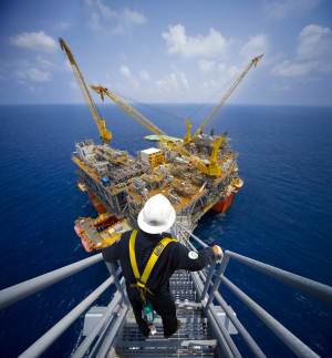 Oil rig worker with oil rig in background - photo courtesy of BP plc.