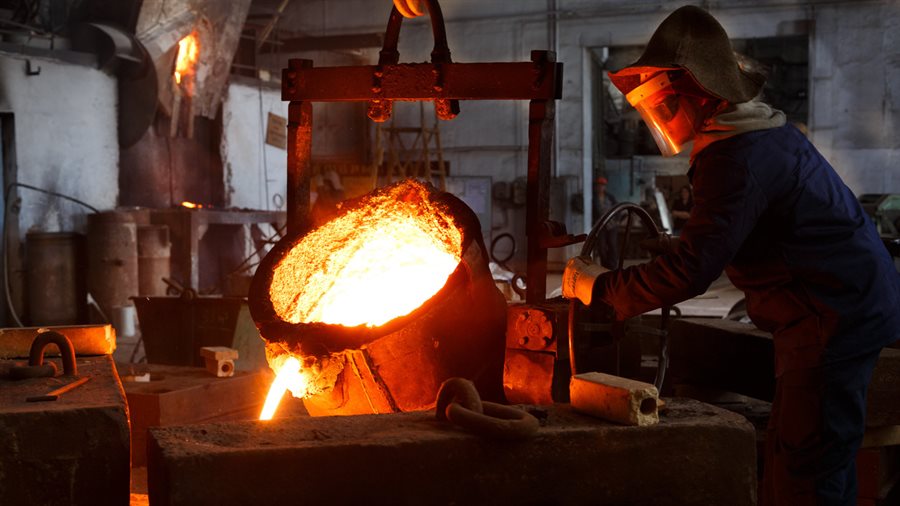 Foundry worker pouring molten metal into a casting