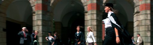 Graduate walking in front of arches