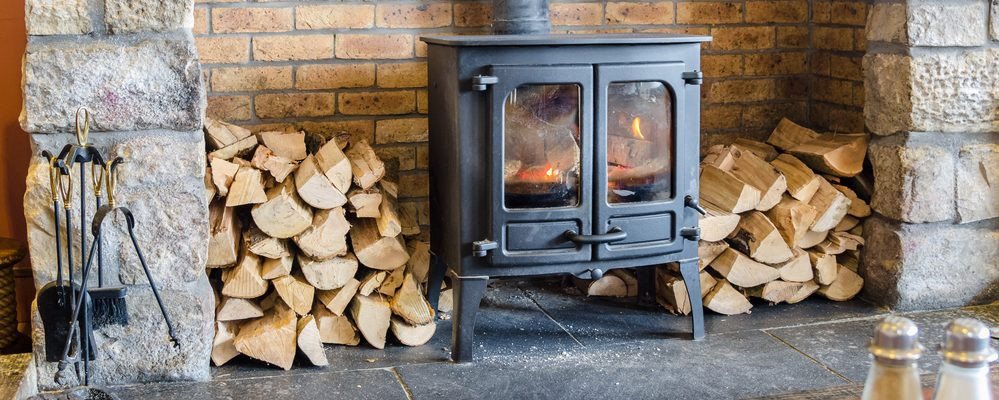 Image of a lit wood burner, set in a fire place.
