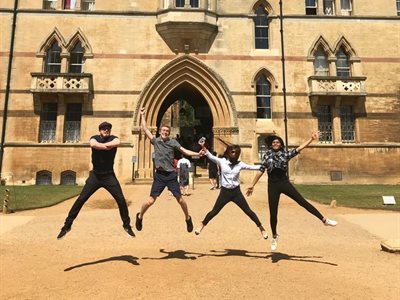Students jumping in the air outside one of the Oxford Colleges