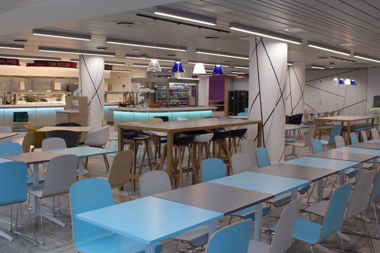 Cafeteria with chairs, tables and a food counter at the back