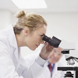 female scientist looking down microscope
