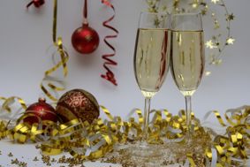 Two champagne glasses surrounded by christmas decorations