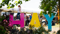 Large multi coloured letters spelling out Hay with a child climbing on them at the festival