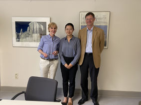 Ms Elke Zeise, Ms Xinyue Xue, Professor Dr Mark von Wietersheim standing for a photo against a wall decorated with modern pictures
