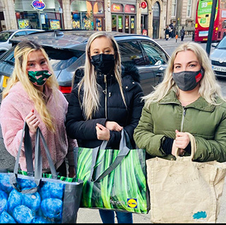Three masked students, volunteering for Action Against Homelessness