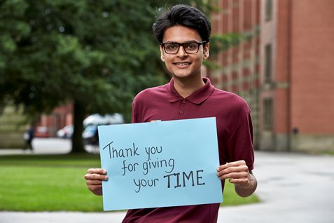 Student outside Aston Webb Building, holding a card saying 'Thank you for giving your time'