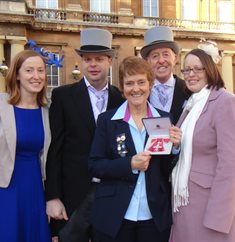 Gill Dawson holding her MBE, surrounded by family