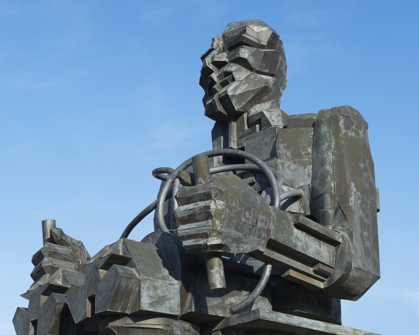 Upper body of seated bronze figure of Faraday sculpture by Eduardo Paolozzi with blue sky background