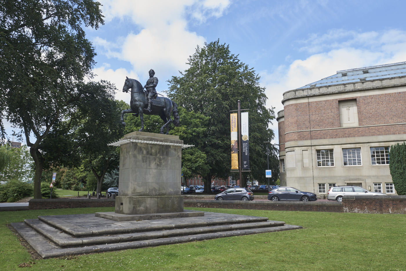 Bronze sculpture of King George I on Horseback by John Nost II on tall concrete plinth in context with Barber Institute in the background to the right