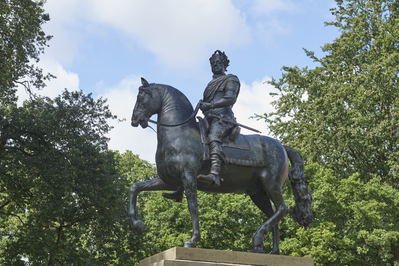 Bronze sculpture of King George I on Horseback by John Nost II with tree foliage in background