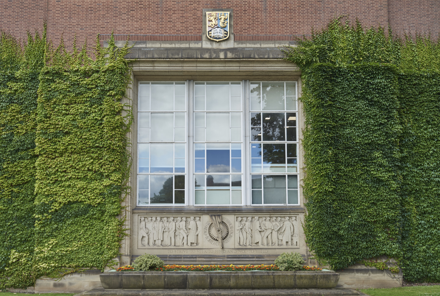 Stone carved Engineering Frieze by William Bloye in context of Engineering Building covered in ivy
