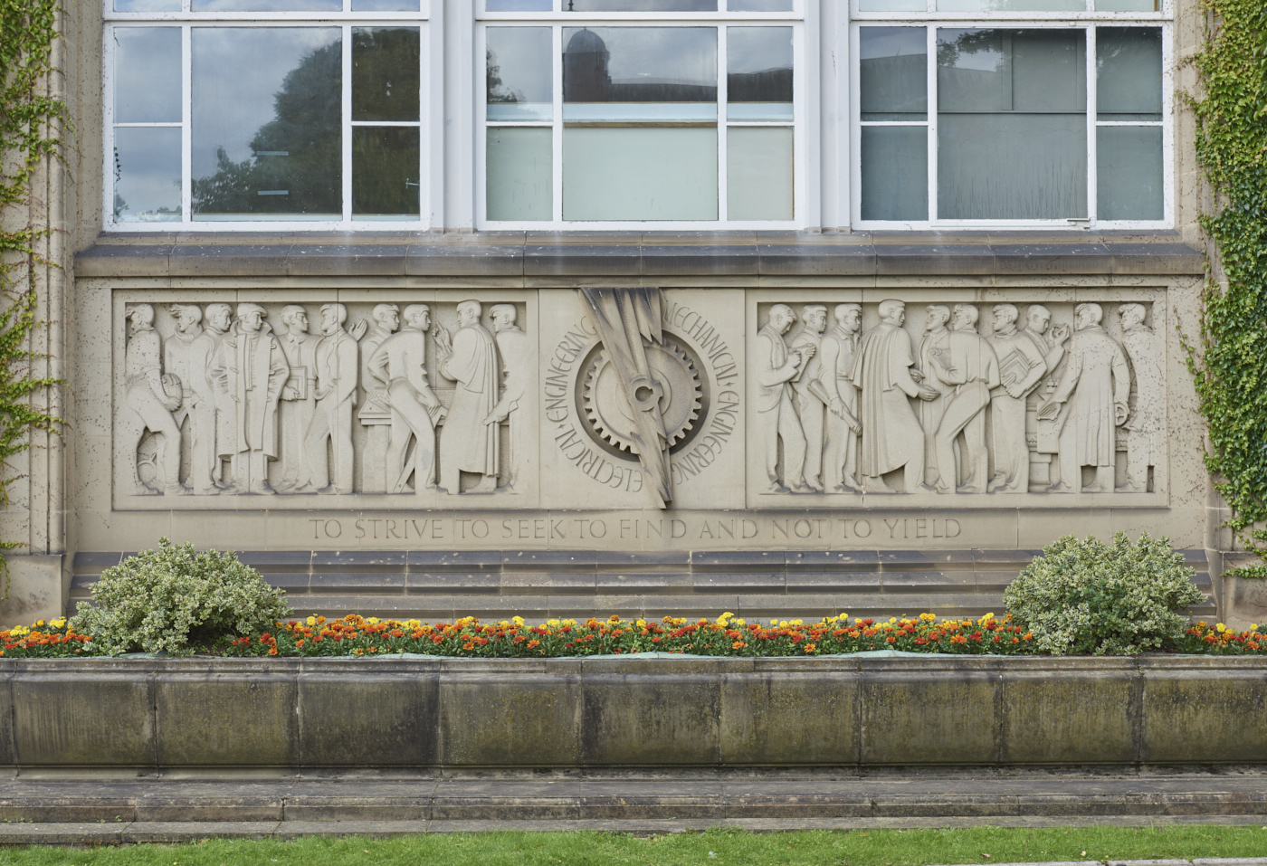 Stone carved Engineering Frieze by William Bloye in context showing flower bed below
