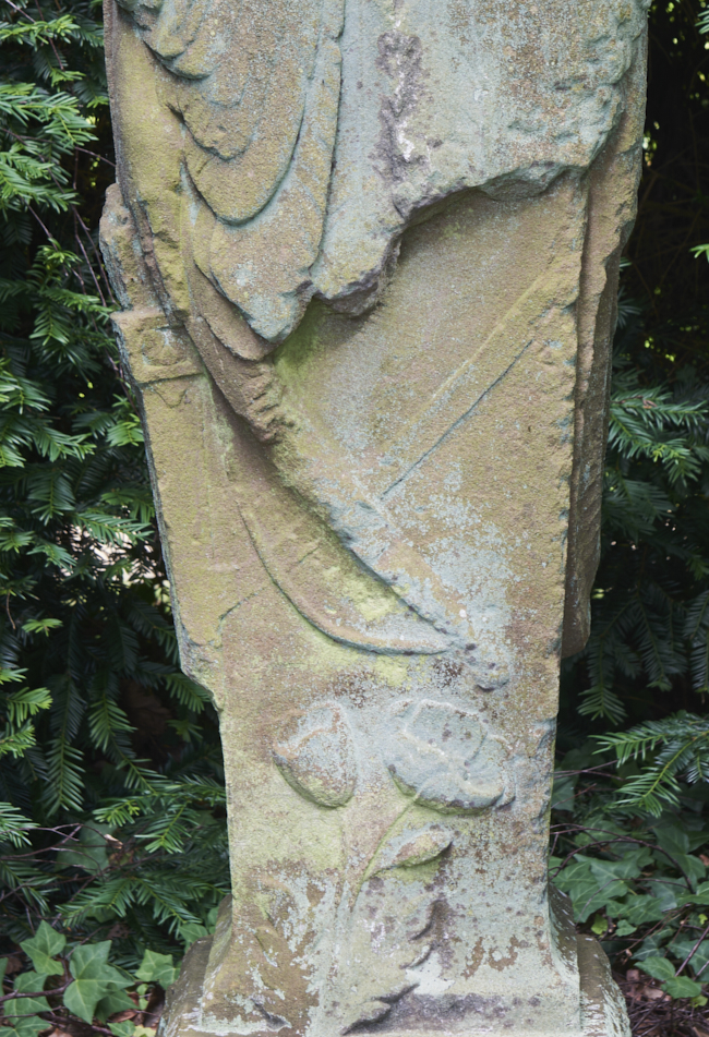 Close up detail of stone sculpture Night by John Cassidy featuring carved stone bow and arrow quiver and flower