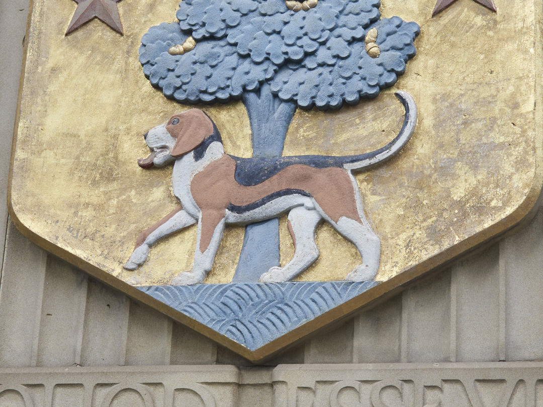 Close up detail of carved and gilded stone heraldic shield set into the wall of the Barber Institute of Fine Arts by Gordon Herickx featuring a beagle