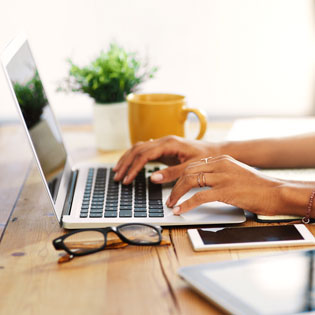 a young woman's hands on the keyboard of a laptop in a fashionable setting