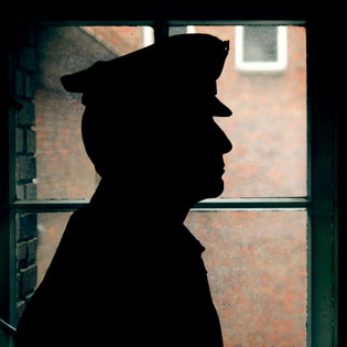A police officer is silhouette against a window
