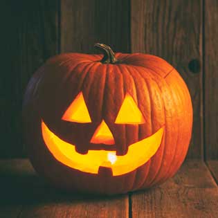 A photo of a Jack 'o' Lantern on a wooden backdrop