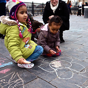 Children drawing on a pavement with chalk in a street