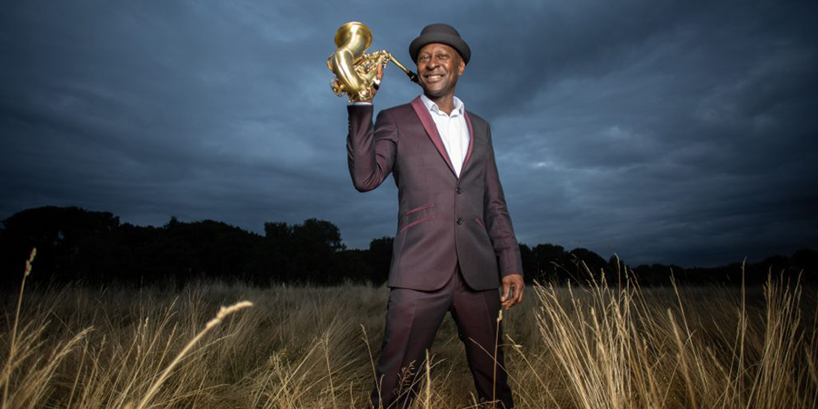 A man in a field holding a brass instrument