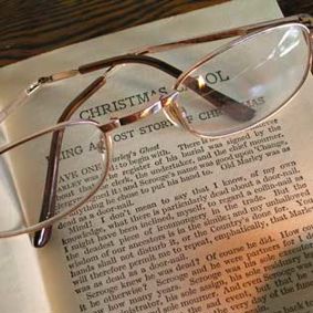 A pair of glasses on top of a Christmas Carol book