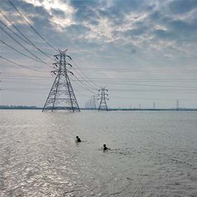 Electricity pylons in a lake, Chennai, India, with two swimmers in front of them