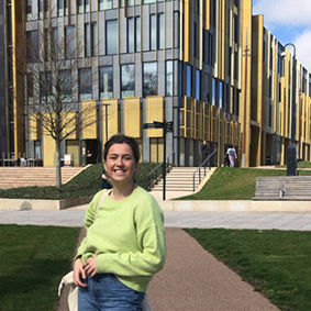Olivia Saunders standing in front of the main Library in the Green Heart on campus