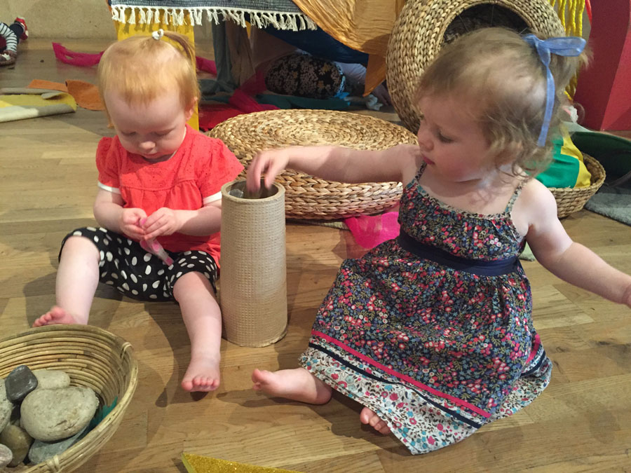 Toddlers play with stones and baskets