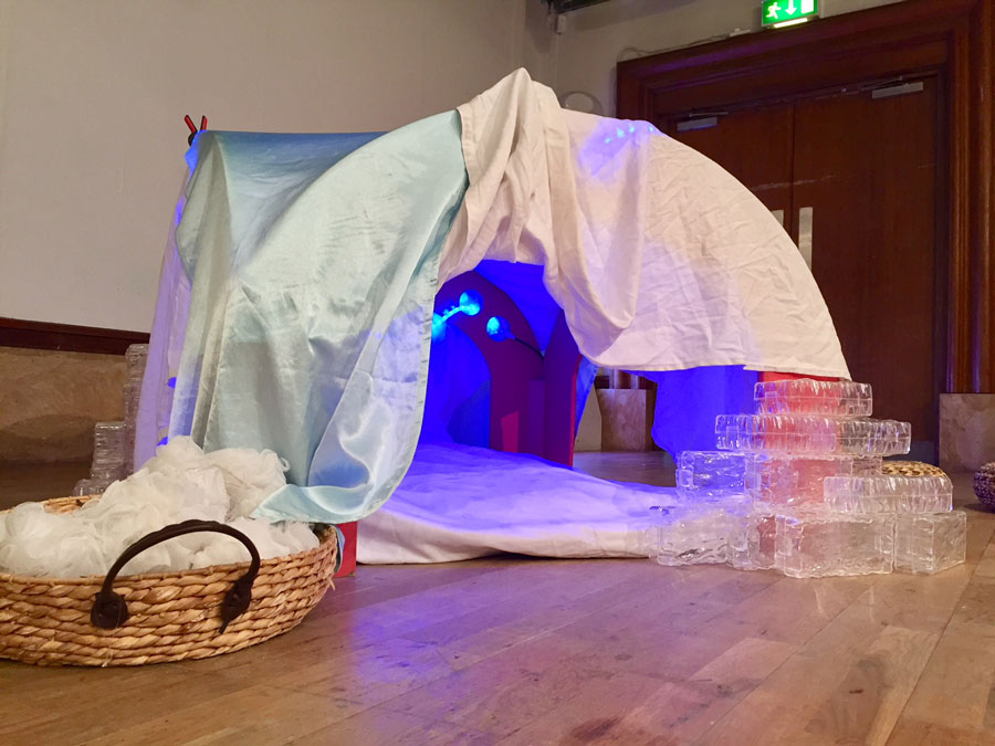 A den made from blankets and filled with blue lights