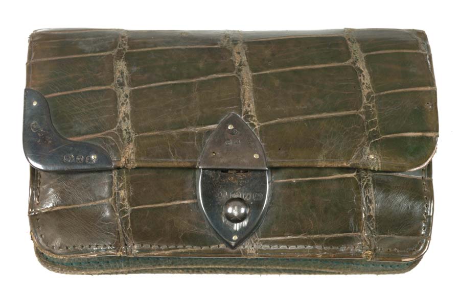Photograph of a small oblong purse, made of repilte skin with silver clasp, and quite battered.