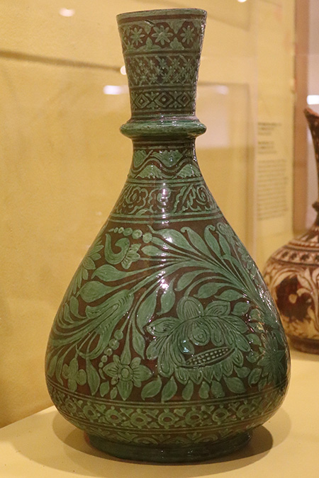 Wonderland Art Pottery (Bombay School of Art) India, Earthenware vase; scrolling floral all-over decoration painted in white slip and covered in a green glaze (c.1880-90), The Potteries Museum & Art Gallery STKMG:CER2539. Photo Credit: The Potteries Museu