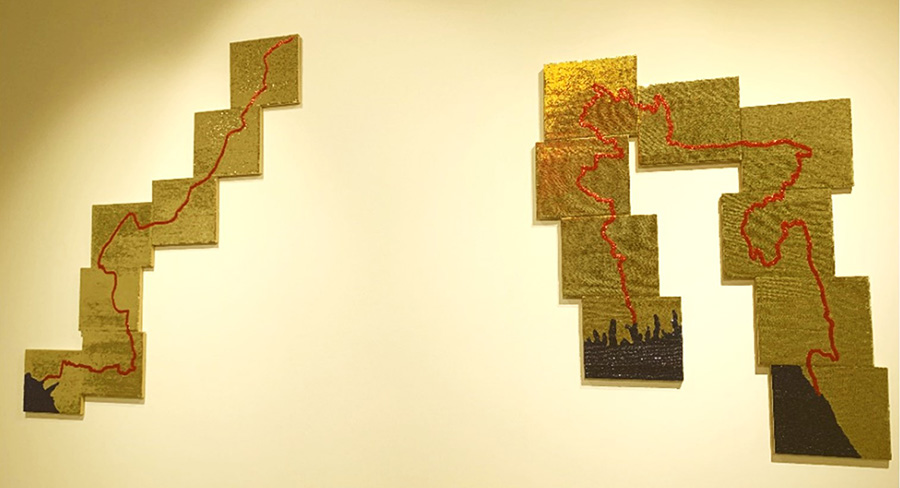Two large shapes made up of bright gold-sequin panels. Each shape contains a line resembling the outline of a country on a map, made up of red sequins. At the bottom of both shapes there are blue sequins representing the sea.