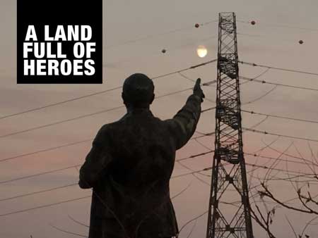 A person pointing at a pylon with the logo of A Land Full of Heroes