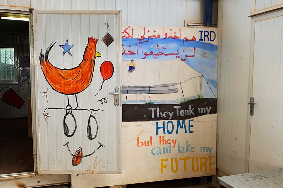 Doors at a refugee camp decorated by children with the words "They can take my home but they can't take my future"