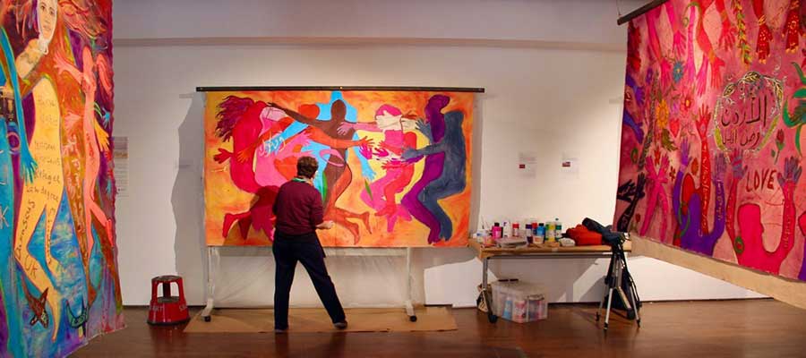Artist Rachel Gadsden working on a Canvas in the gallery with large paintings either side.