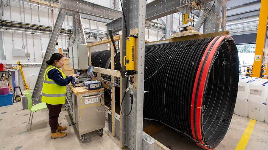 Researcher standing next to pipe fitted with optical fibre to monitor condition of concrete lining