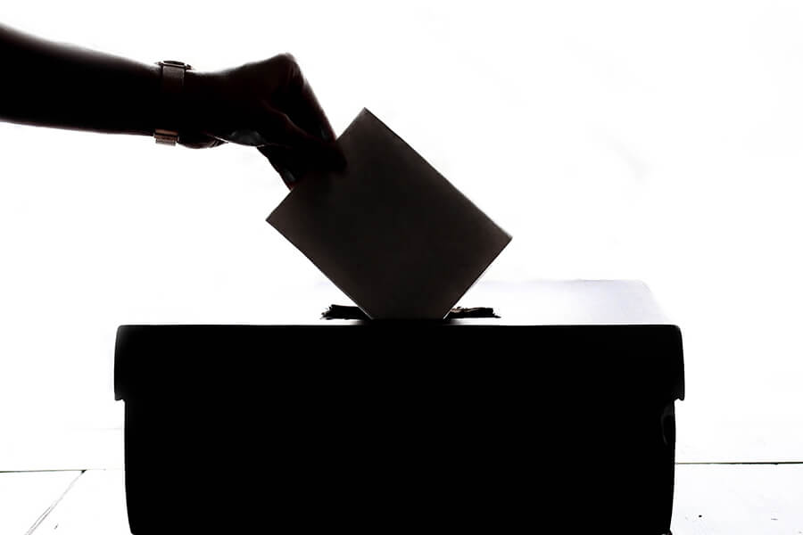 Silhouette of person placing ballot paper in ballot box