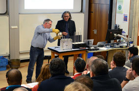 Professor Nick Green (right) with support from his research technician (left) carries out a casting process in front of a room of people at his Inaugural Lecture